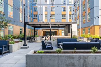 A modern outdoor seating area with a concrete planter in the foreground and a building in the background.